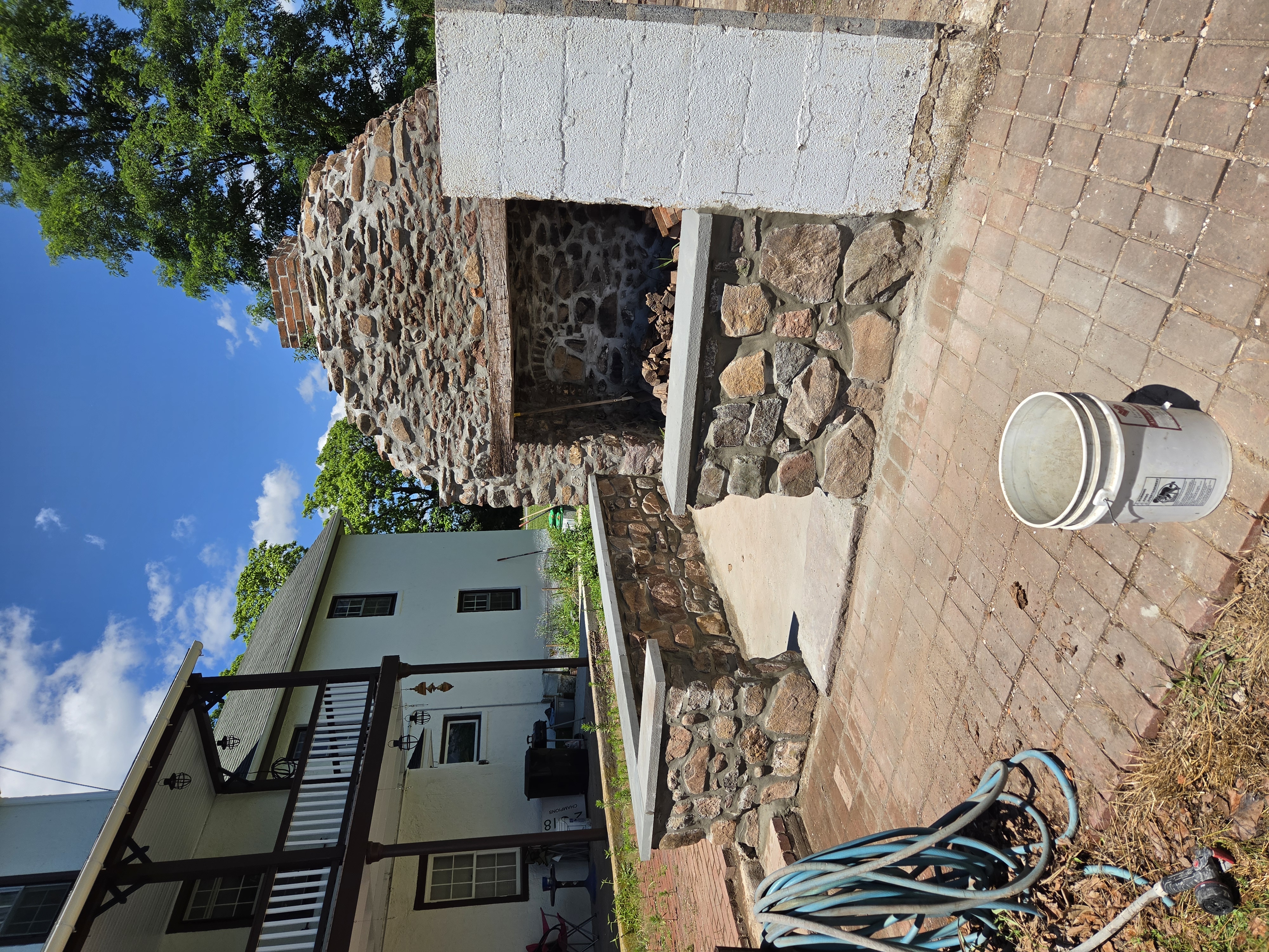 Finished stone sitting walls surrounding an 1800s outdoor kitchen fireplace in Birdsboro Pennsylvania
